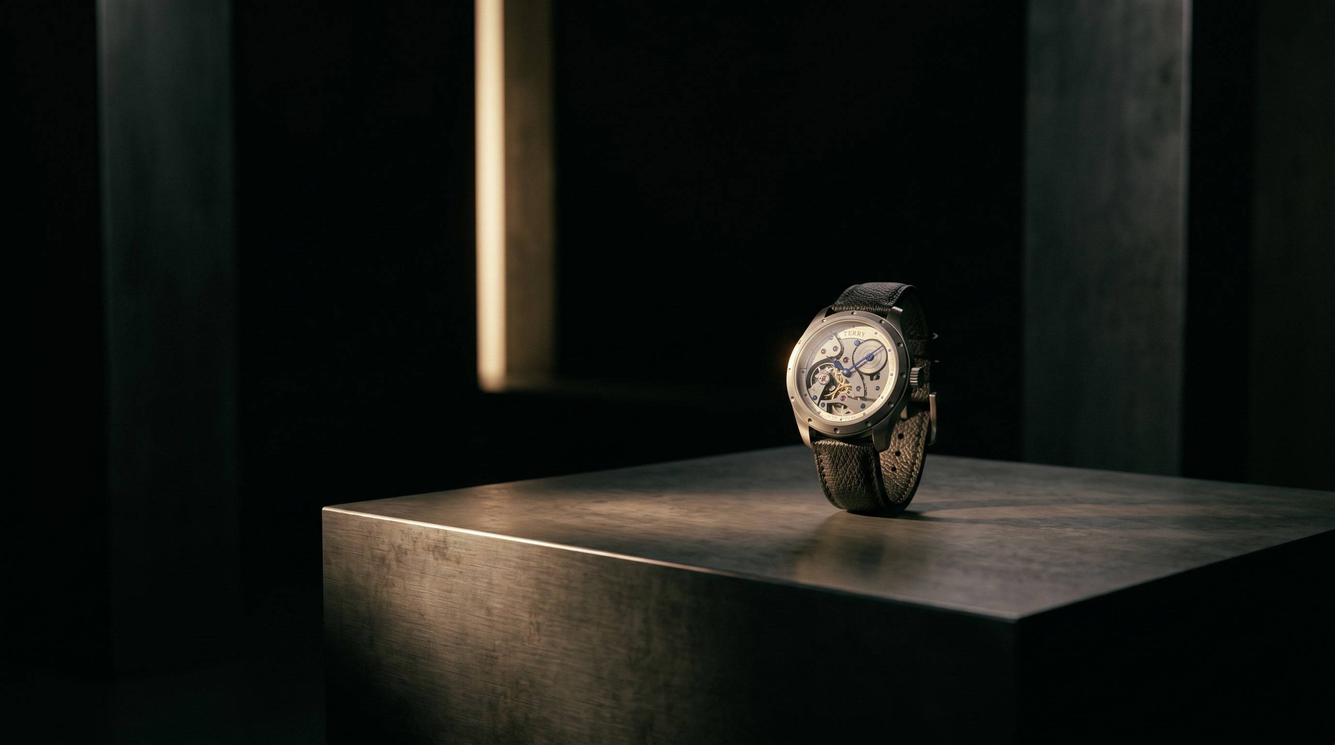 The Terry Timepiece resting on a steel plinth in a darkened gallery, a single vertical light falling across the room behind it.